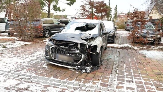 Ein abgebranntes Auto auf einem Hotelparkplatz. © Screenshot 