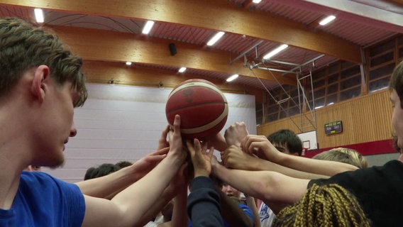 Mehrere Hände halten einen Basketball hoch. Mehrere Hände halten einen Basketball hoch. © Screenshot