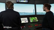 Zwei junge Männer stehen in einem Schiffsimulator. © Screenshot 
