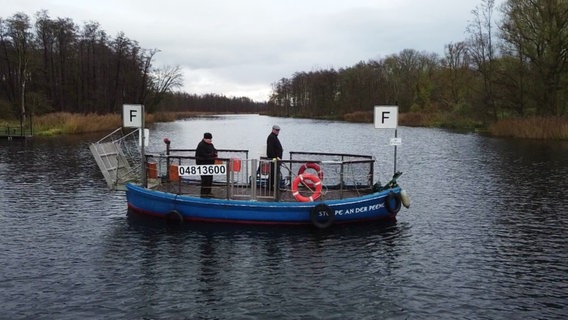 Blaues Schiff fährt über einen Fluss, darauf zwei Personen. © Screenshot 