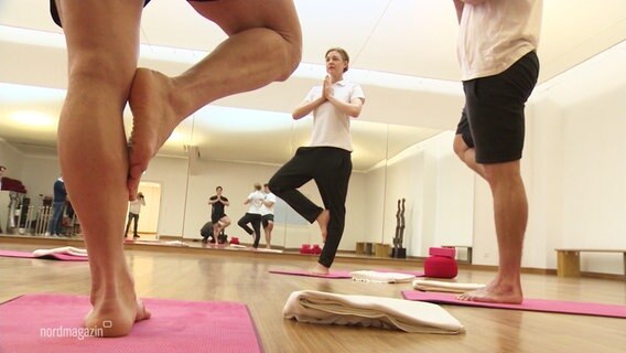 Mehrere Personen balancieren beim Yoga auf einem Bein. © Screenshot 