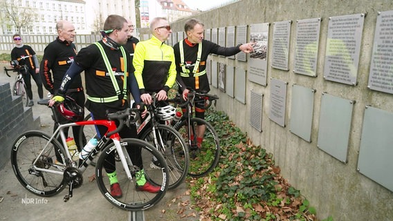 Mehrere Radfahrer schauen auf eine Gedenktafel. © Screenshot 