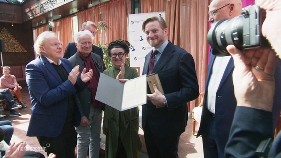 Szczepan Twardoch hält den Literaturpreis in der Hand. © Screenshot 