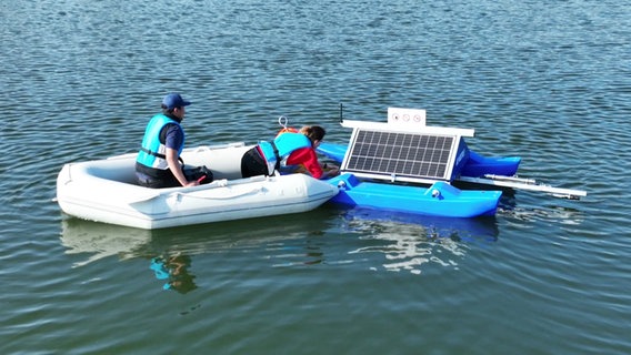 Zwei Personen in Schwimmwesten befestigen eine Messstation auf dem Kosenowsee. © Screenshot 