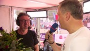 Willi Hark mit einem Blumenstrauß im Gespräch mit Andreas Käckell © Screenshot 
