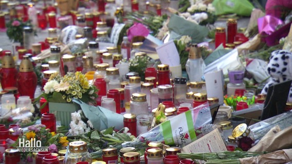Kerzen und Blumen liegen auf dem Boden. © Screenshot 