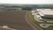Auf einer Straßenseite befindet sich ein Acker, auf der anderen ein Gewerbegebiet. © Screenshot 