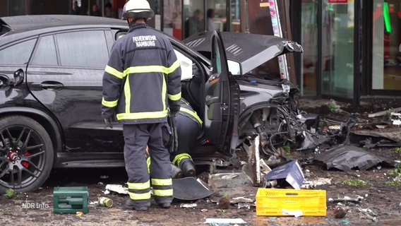 Zwei Feuerwehrmänner untersuchen einen verunfallten Pkw. © Screenshot 