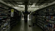 Eine Frau steht in einem dunklen Supermarkt. © Screenshot 