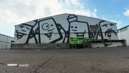 Eine Hauswand mit Graffiti des Künstlers Rebelzer im Hamburger Hafen. © Screenshot 