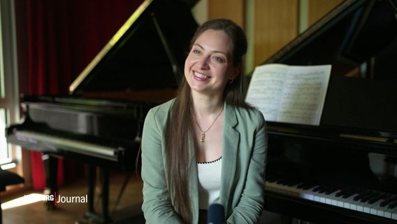 Die Pianistin Daria Parkhomenko sitzt am Klavier und lacht ins die Kamera. © Screenshot 