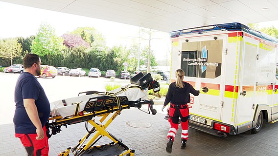 Zwei Mitarbeiter des Rettungsdienstes Landkreis Harburg haben gerade einen Patienten in die Notaufnahme des Krankenhauses Winsen (Luhe) gebracht und fahren zum nächsten Einsatz. © Screenshot 