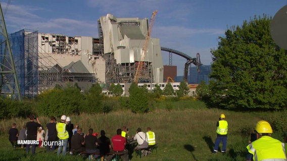 Mehrere Menschen beobachten die Sprengung des zweiten Kesselhauses am Kraftwerk Moorburg. © Screenshot 