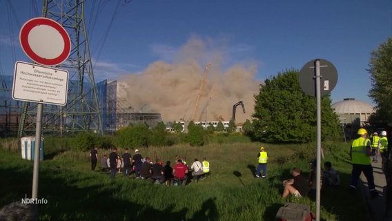 Menschen vor einer Staubwolke der Sprengung des Kesselhauses in Moorburg. © Screenshot 