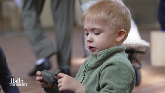 Ein Kind spielt mit einem Spielzeug-Nilpferd beim Kirchentag in Hannover. © Screenshot 