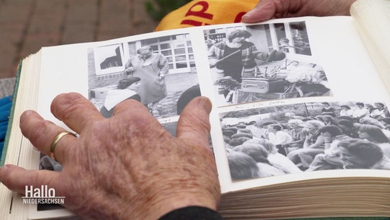 Eine Frau blättern in einem Fotoalbum mit alten Schwarz-Weiß-Fotos. © Screenshot 