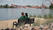 Ein Paar sitzt auf einer Bank und schaut aufs Wasser. © Screenshot 