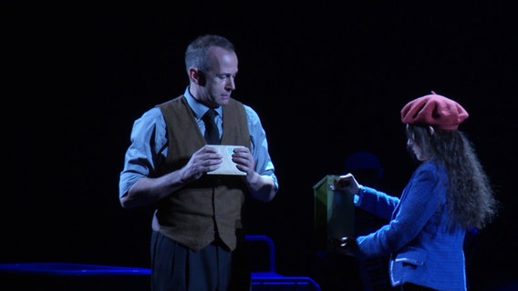 Ein Mann und eine junge Frau auf einer Theaterbühne. © Screenshot 