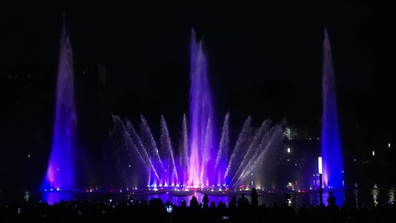 Lila angeleuchtete Wasserfontänen. © Screenshot 