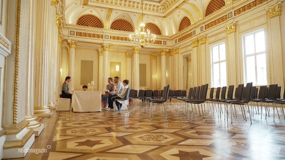 Ein Paar wird in einem großen goldenen Saal getraut. © Screenshot 