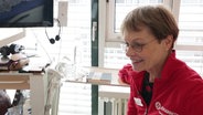 Ein Frau in einer roten Jacke in einem Krankenhauszimmer. © Screenshot 