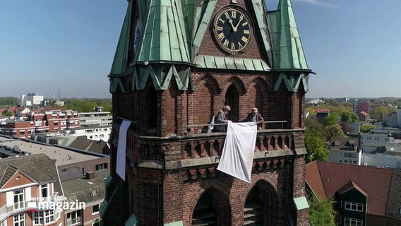 Weiße Lacken hängen an allen Seiten des Kirchturms in Elmshorn, um an die Aktion "Weiße Flagge" zum Kriegsende 1945 zu gedenken. © Screenshot 
