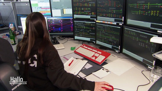 Blick über die Schulter einer Fahrdienstleiterin. Sie sitzt vor zahlreichen Monitoren, die Teil der neuen Bahn-Schaltzentrale sind in Osnabrück. © Screenshot 