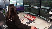 Blick über die Schulter einer Fahrdienstleiterin. Sie sitzt vor zahlreichen Monitoren, die Teil der neuen Bahn-Schaltzentrale sind in Osnabrück. © Screenshot 