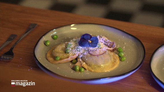 Selbstgemachte Ravioli, angerichtet auf einem Teller und dekoriert mit einer Blüte. © Screenshot 