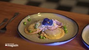 Selbstgemachte Ravioli, angerichtet auf einem Teller und dekoriert mit einer Blüte. © Screenshot 