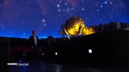 Eine Person steht im Innenraum des Hamburger Planetariums. © Screenshot 