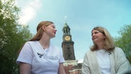 Zwei Frauen unterhalten sich. Im Hintergrund ist der Hamburger Michel zu sehen. © Screenshot 