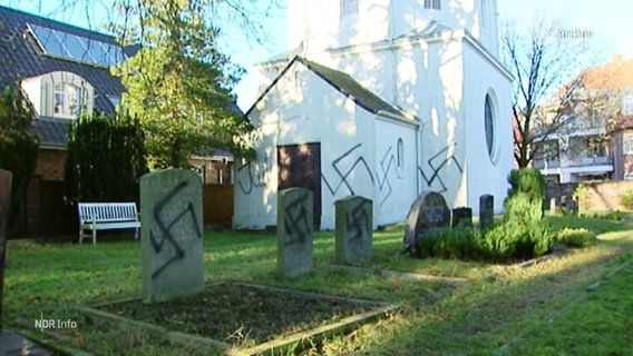 Grabsteine vor einer Kapelle - beides mit Hakenkreuzen beschmiert. © Screenshot 
