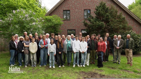 Eine Familie hat sich für ein Foto in einem Garten versammelt. © Screenshot 