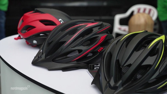 Drei Fahrradhelme liegen auf einem Tisch. © Screenshot 