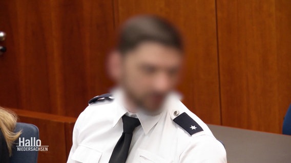 Der angeklagte Polizeibeamte vor Gericht. Sein Gesicht ist unkenntlich gemacht. © Screenshot 
