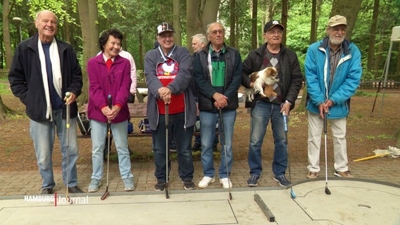 Mehrere Seniorinnen und Senioren stehen neben einer Minigolfbahn. © Screenshot 