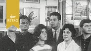 Studenten stehen 1960 vor einer Wand mit verschiedenen Gemälden. © Screenshot 