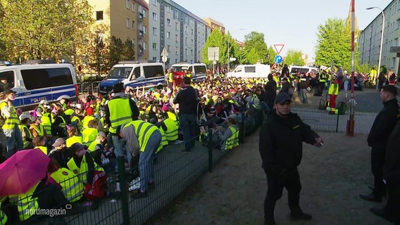 Demonstrierende sitzen auf einer Straße. © Screenshot 