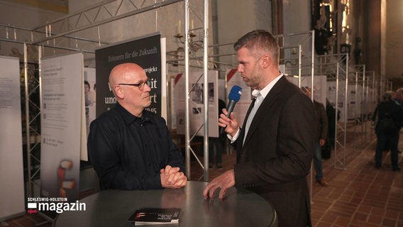 Reporter Phillip Kamke interviewt einen der Initiatoren der Gedenkveranstaltung in der Lübecker Marienkirche. © Screenshot 