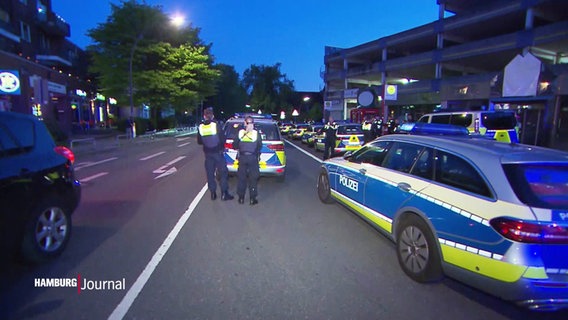 Mehrere Polizeibeamte und -wagen stehen auf einer Straße. © Screenshot 