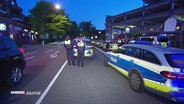 Mehrere Polizeibeamte und -wagen stehen auf einer Straße. © Screenshot 