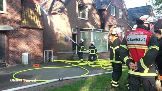 Feuerwehrleute beim Löschen in einer Wohngegend. © Screenshot 