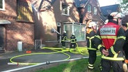 Feuerwehrleute beim Löschen in einer Wohngegend. © Screenshot 
