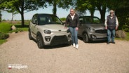 Eine junge Frau und ein älterer Mann stehen neben ihrem Microcar. © Screenshot 