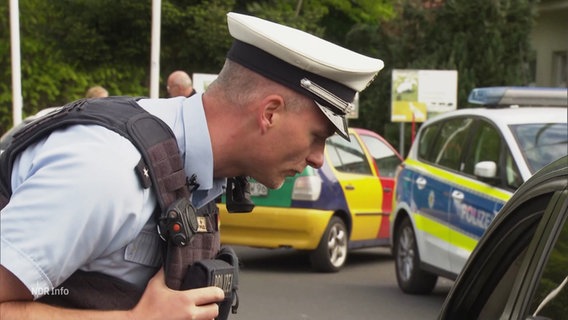 Ein Polizeibeamter kontrolliert ein Fahrzeug. © Screenshot 