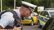 Ein Polizeibeamter kontrolliert ein Fahrzeug. © Screenshot 