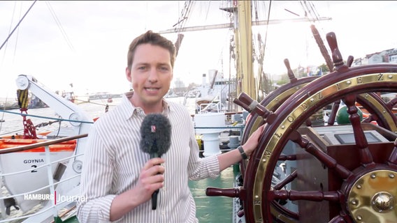 NDR Reporter Simon Ritter steht an Bord eines Schiffes. © Screenshot 