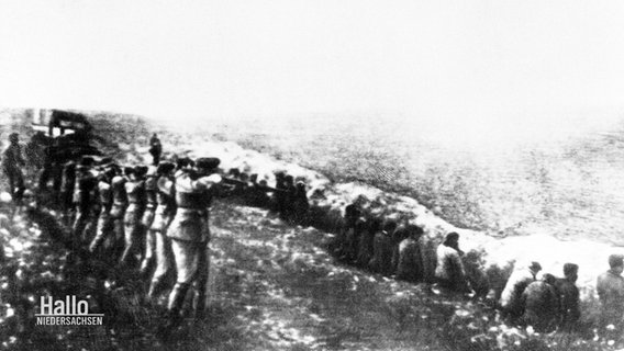 Ein historisches Schwarz-Weiß-Foto zeigt eine Massenerschießung in einem Krieg. © Screenshot 
