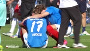 Nach einem verlorenen Spiel sitzt ein Spieler des Vereins Holstein Kiel mit der Nummer 17 und dem Namen "Becker" auf dem Rasen und wird von einem Mitspieler getröstet. © Screenshot 